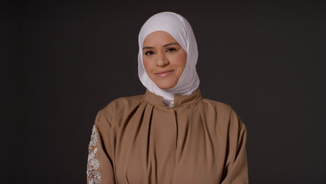 Studioporträt-Einer-Lächelnden-Muslimischen-Frau-Mit-Hijab-Vor-Schlichtem,-Dunklem-Hintergrund-1